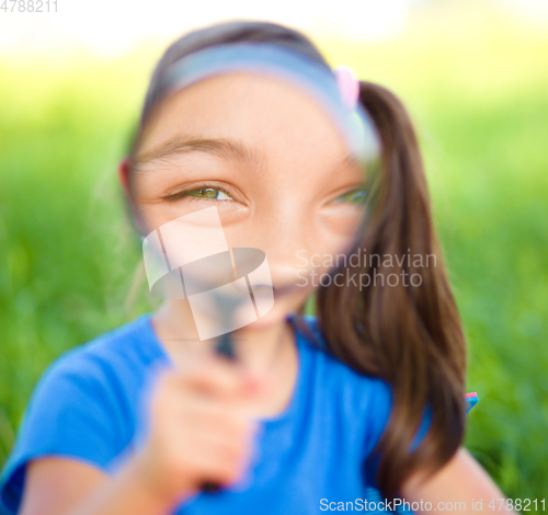 Image of Little girl is looking through magnifier