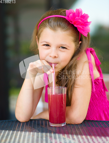 Image of Little girl is drinking cherry juice