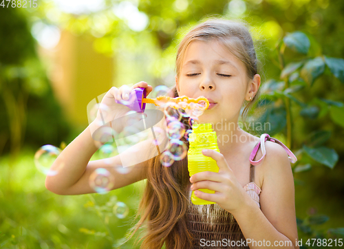 Image of Little girl is blowing a soap bubbles