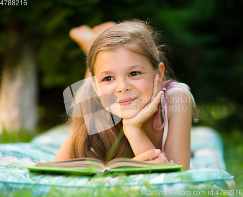 Image of Little girl is reading a book outdoors