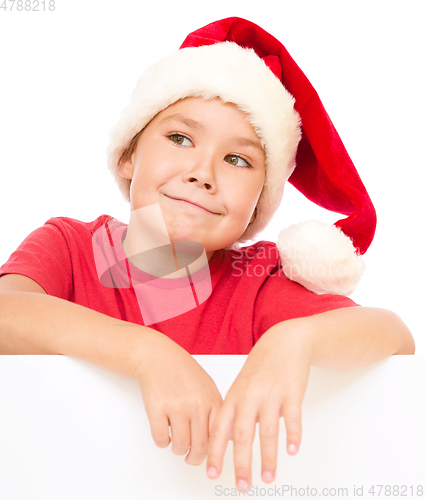 Image of Little girl in santa hat is holding blank board