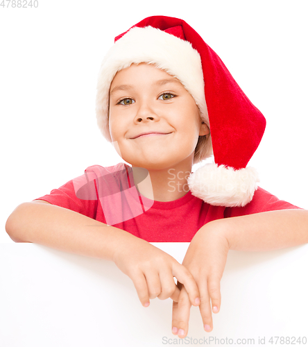 Image of Little girl in santa hat is holding blank board