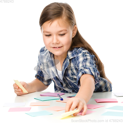 Image of Girl is writing on color stickers using pen