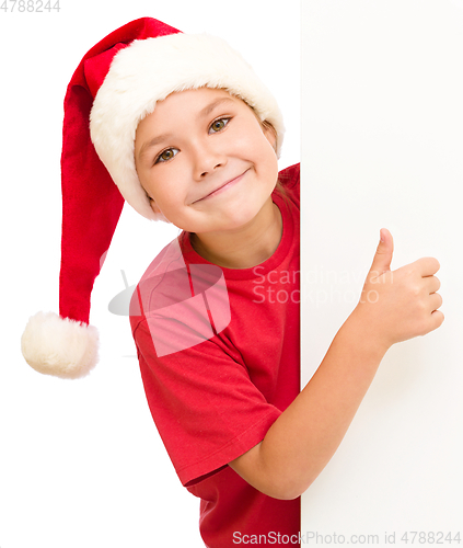 Image of Little girl in santa hat is holding blank board