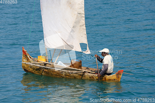 Image of Malagasy man on sea in traditional handmade dugout wooden sailin