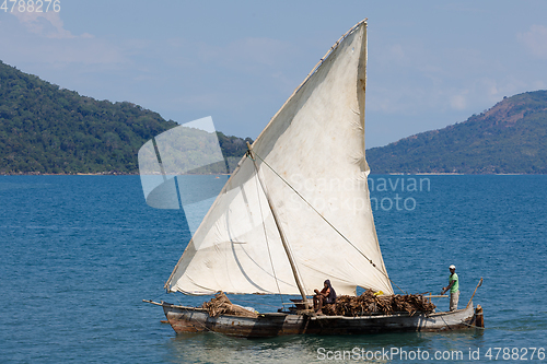 Image of Malagasy man on sea in traditional handmade dugout wooden sailin