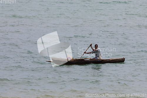 Image of Malagasy man on sea in traditional handmade dugout wooden boat