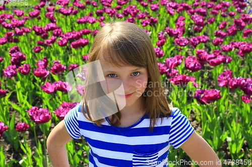 Image of little girl stand by lilac tulips