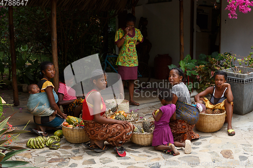 Image of Malagasy women preparing basket of fruit for street market sale,