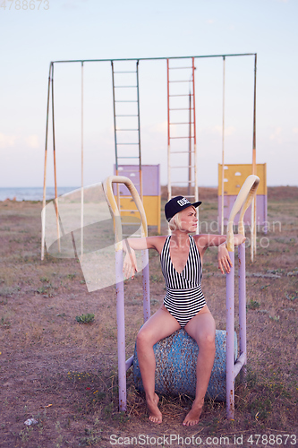 Image of Beautiful woman in black and white striped swimsuit on the old sports ground. Film effect.