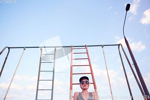 Image of Beautiful woman in black and white striped swimsuit on the old sports ground. Film effect.