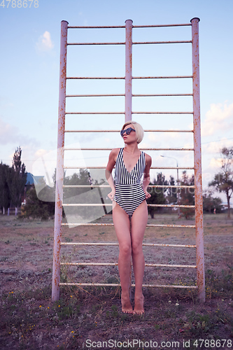 Image of Beautiful woman in black and white striped swimsuit on the old sports ground. Film effect.
