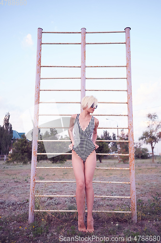 Image of Beautiful woman in black and white striped swimsuit on the old sports ground. Film effect.