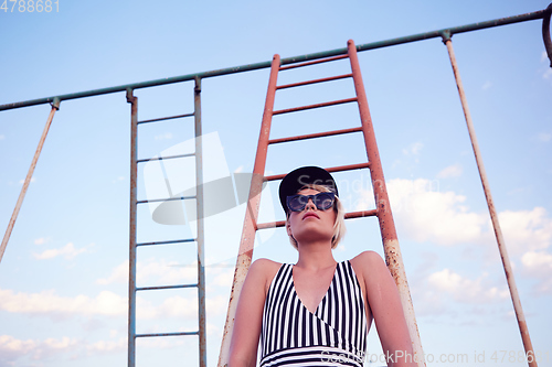 Image of Beautiful woman in black and white striped swimsuit on the old sports ground. Film effect.