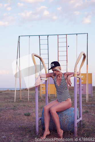 Image of Beautiful woman in black and white striped swimsuit on the old sports ground. Film effect.