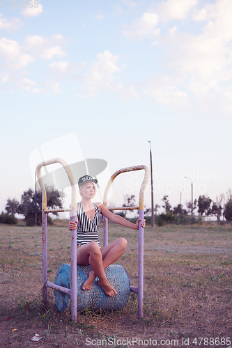 Image of Beautiful woman in black and white striped swimsuit on the old sports ground. Film effect.