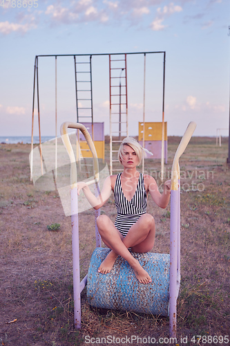 Image of Beautiful woman in black and white striped swimsuit on the old sports ground. Film effect.