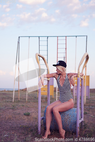 Image of Beautiful woman in black and white striped swimsuit on the old sports ground. Film effect.