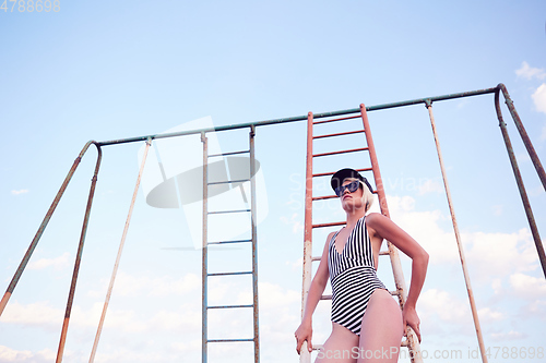 Image of Beautiful woman in black and white striped swimsuit on the old sports ground. Film effect.