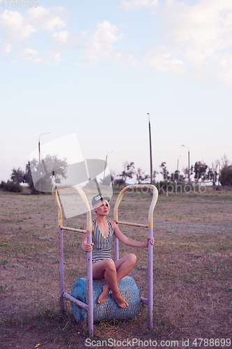 Image of Beautiful woman in black and white striped swimsuit on the old sports ground. Film effect.