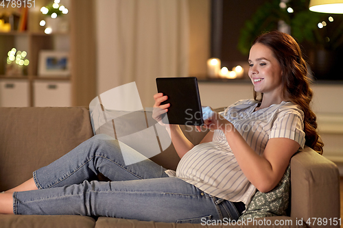 Image of happy pregnant woman with tablet pc at home
