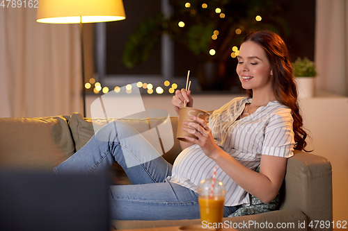 Image of pregnant woman watching tv and eating wok at home