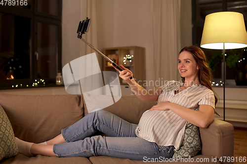 Image of happy smiling pregnant woman taking selfie at home