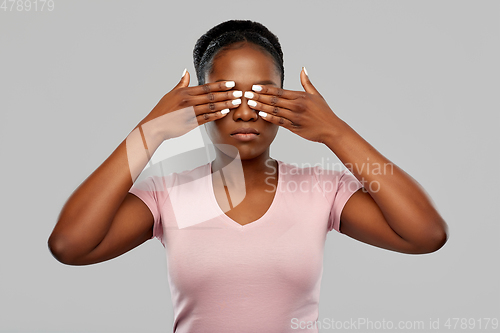Image of african american woman with eyes closed by hands