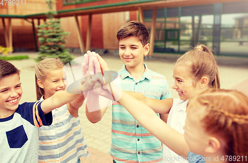 Image of group of children making high five at school yard