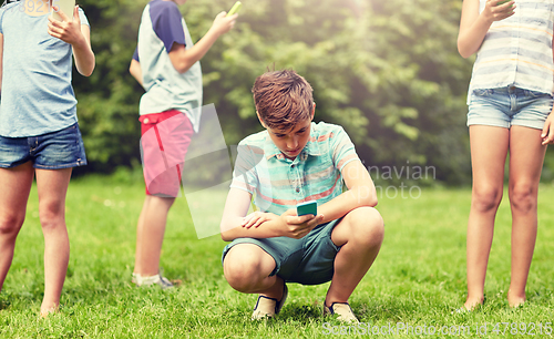 Image of kids with smartphones playing game in summer park