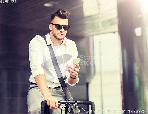 Image of man with bicycle and smartphone on city street