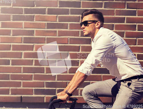 Image of young man riding bicycle on city street