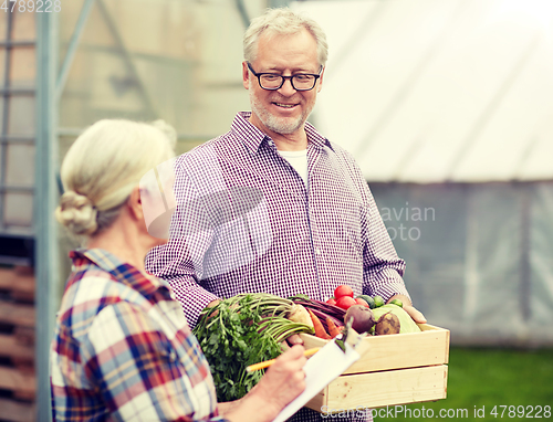 Image of senior couple with box of vegetables on farm