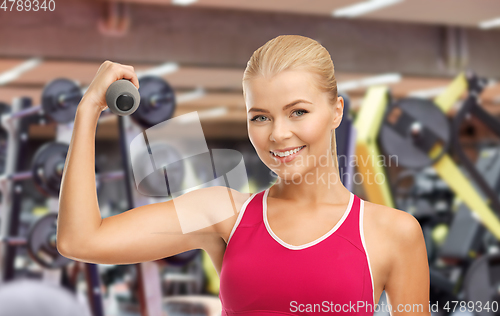 Image of happy young woman with dumbbells exercising in gym