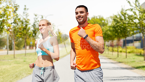 Image of happy couple with fitness trackers running outdoor