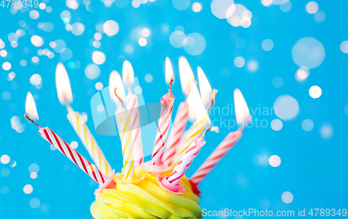 Image of birthday cupcake with many burning candles