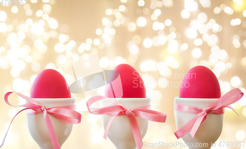 Image of pink easter eggs in holders over festive lights