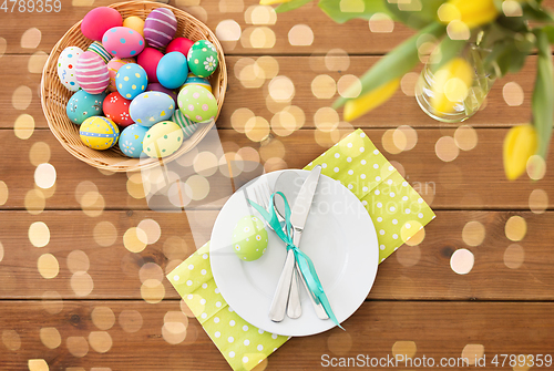 Image of easter eggs in basket, plates, cutlery and flowers