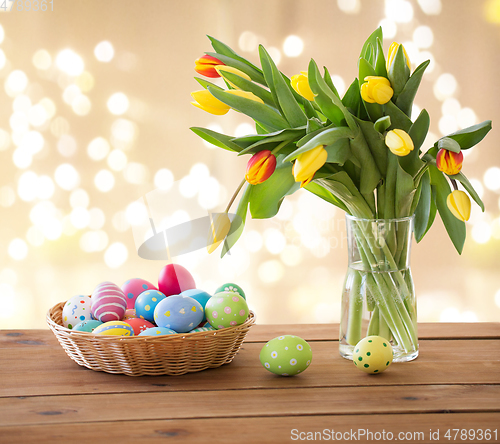 Image of colored easter eggs in basket and tulip flowers