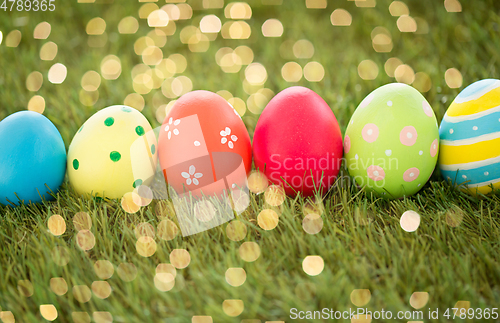 Image of row of colored easter eggs on artificial grass