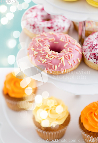 Image of close up of glazed donuts and cupcakes on stand