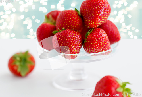 Image of strawberries on glass stand over white background