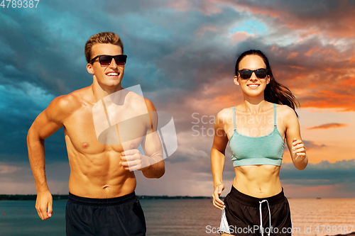 Image of couple with earphones running over sea