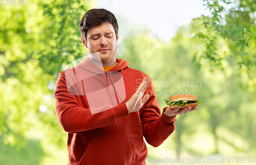 Image of young man refusing from hamburger