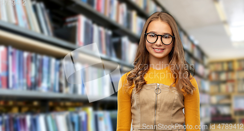 Image of smiling teenage student girl in glasses at library