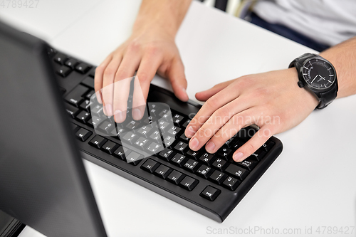 Image of male hands typing on computer keyboard on table