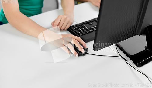 Image of female hand with computer mouse on table