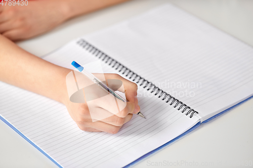 Image of hands of student girl with pen writing to notebook