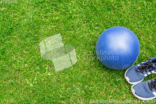 Image of Fitness ball and sneakers on the green grass background