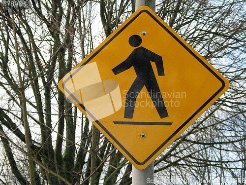 Image of yellow pedestrian sign in front of trees